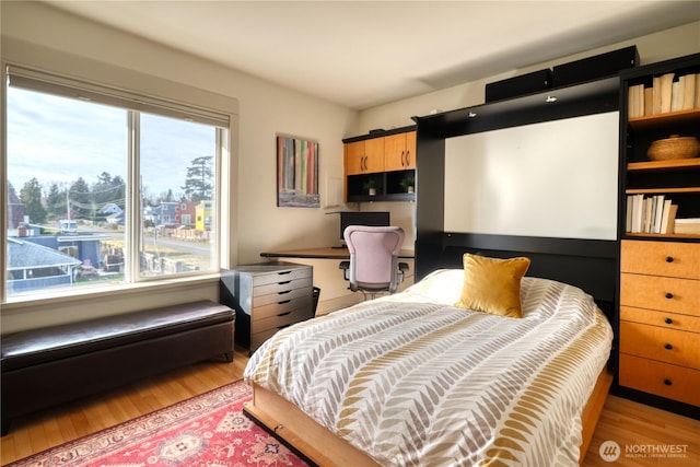 bedroom featuring light wood finished floors and built in study area