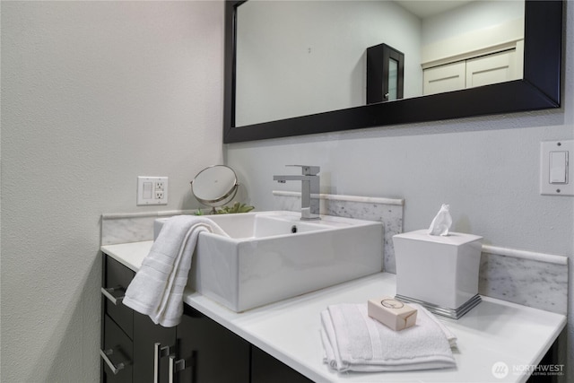 bathroom featuring a textured wall and vanity