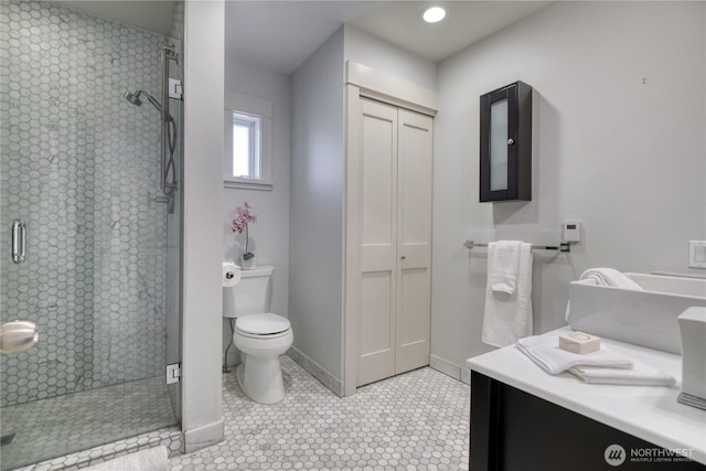 bathroom with toilet, a shower stall, baseboards, and tile patterned floors