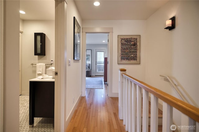 hall with recessed lighting, light wood-type flooring, an upstairs landing, and baseboards