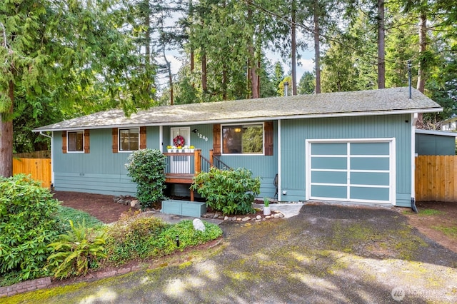 ranch-style home with aphalt driveway, an attached garage, and fence