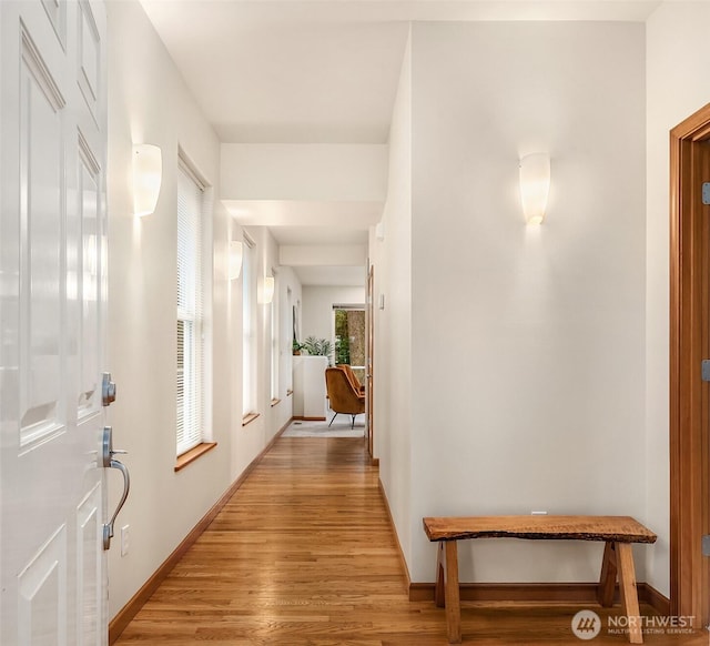 hallway featuring light wood-style flooring and baseboards