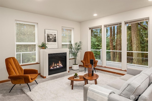 living area featuring carpet floors, a glass covered fireplace, baseboards, and recessed lighting