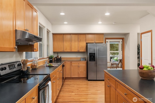 kitchen featuring stainless steel appliances, dark countertops, light wood-style floors, a sink, and under cabinet range hood