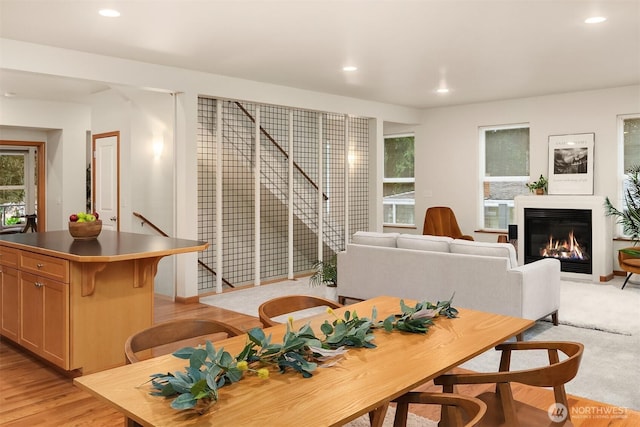 dining area with light wood-style floors, a glass covered fireplace, and recessed lighting