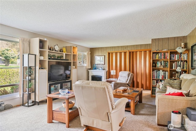 living area with wood walls, a fireplace, a textured ceiling, and carpet floors