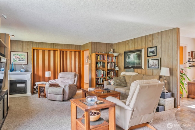 carpeted living room with a glass covered fireplace, wood walls, and a textured ceiling