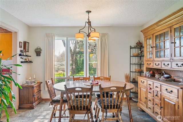 dining area with a chandelier, a textured ceiling, and baseboards