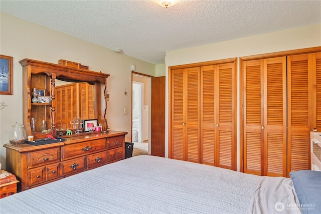 bedroom with a textured ceiling and multiple closets