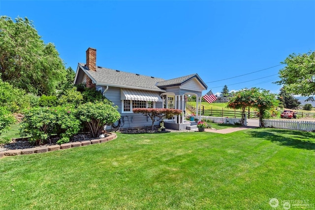 back of property with a lawn, a chimney, and fence