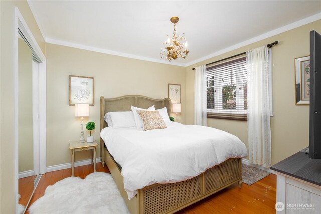 bedroom featuring ornamental molding, wood finished floors, a closet, baseboards, and a chandelier