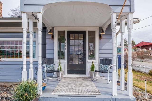 property entrance with a porch and fence