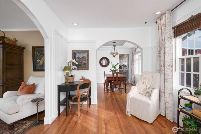 living area featuring arched walkways and light wood-style floors