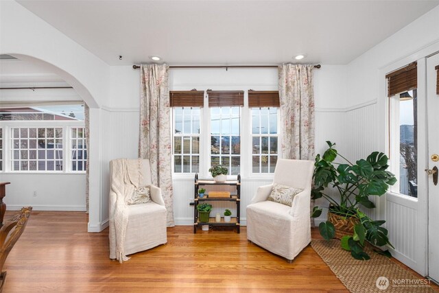 sitting room with visible vents, light wood finished floors, recessed lighting, arched walkways, and wainscoting