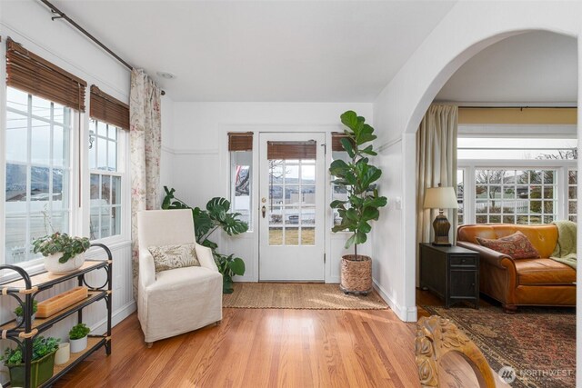 living area with arched walkways and wood finished floors