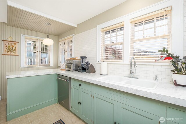 kitchen featuring a sink, tasteful backsplash, light countertops, light tile patterned floors, and hanging light fixtures