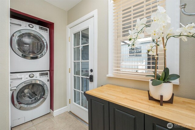 washroom with light tile patterned flooring, laundry area, and stacked washing maching and dryer