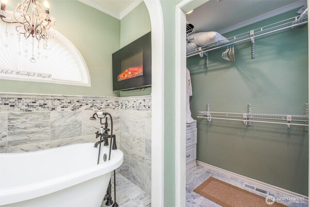 bathroom with a freestanding tub, visible vents, marble finish floor, and a spacious closet