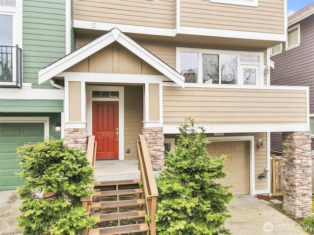 view of exterior entry featuring a garage, stone siding, and a balcony