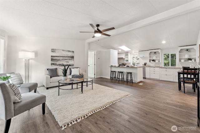 living room with baseboards, a ceiling fan, wood finished floors, vaulted ceiling with beams, and a textured ceiling