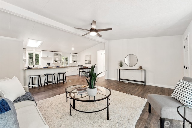 living room featuring lofted ceiling with beams, ceiling fan, baseboards, and dark wood-style flooring