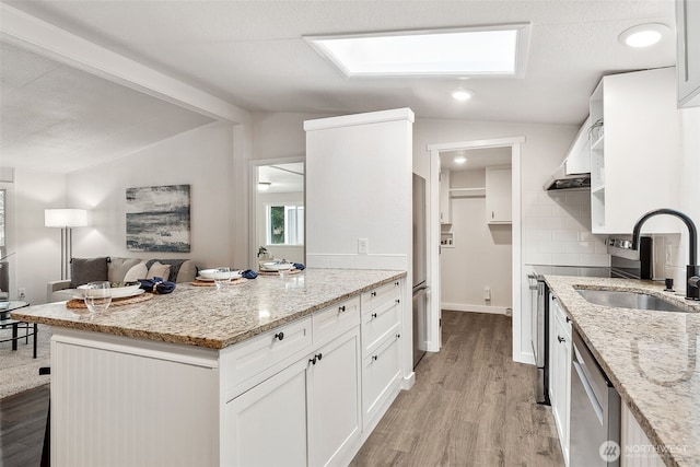 kitchen with lofted ceiling with beams, dishwasher, light wood-style flooring, and a sink