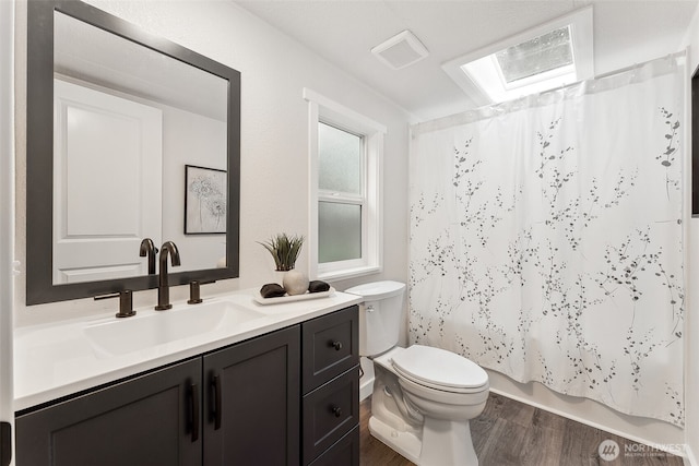 bathroom featuring visible vents, toilet, shower / bath combo, vanity, and wood finished floors