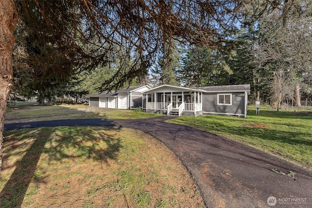 view of front facade with a front yard, a sunroom, an outdoor structure, and an attached garage