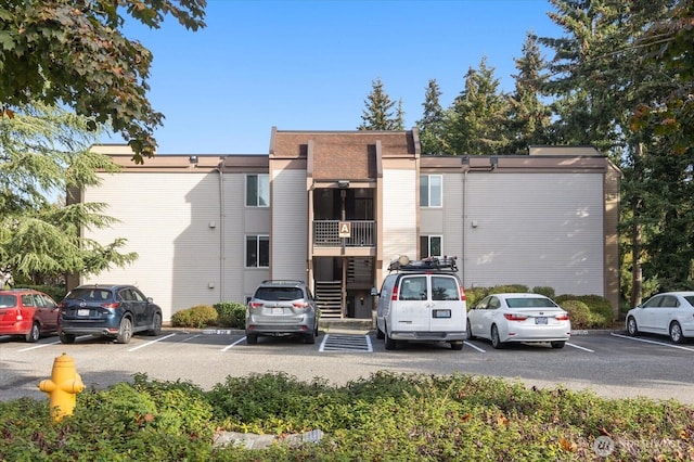 view of property featuring uncovered parking and stairway