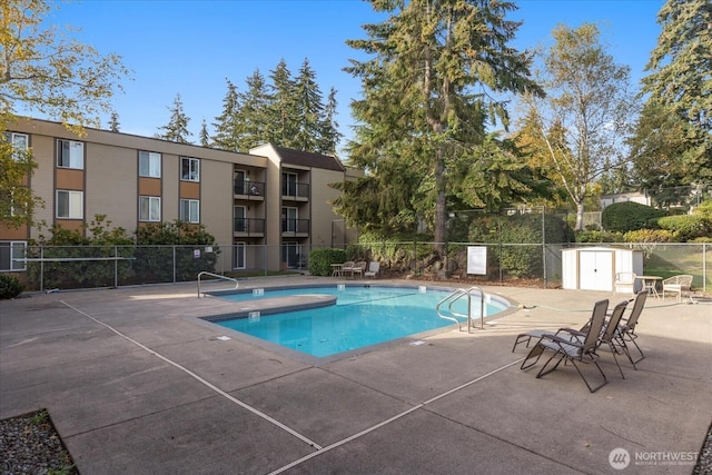 community pool with a patio area and fence