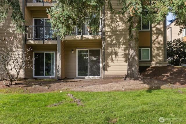 rear view of house with a balcony and a lawn