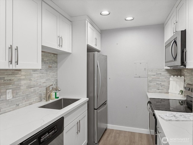 kitchen with stainless steel appliances, white cabinetry, a sink, and baseboards