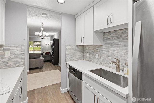 kitchen featuring appliances with stainless steel finishes, white cabinets, a sink, and light wood finished floors