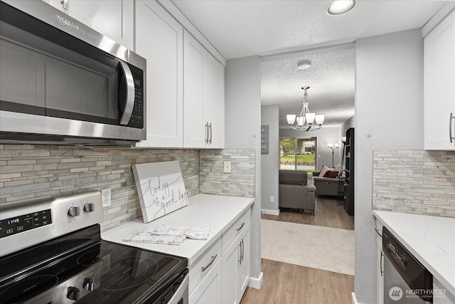 kitchen featuring stainless steel appliances, a chandelier, white cabinetry, and light wood finished floors