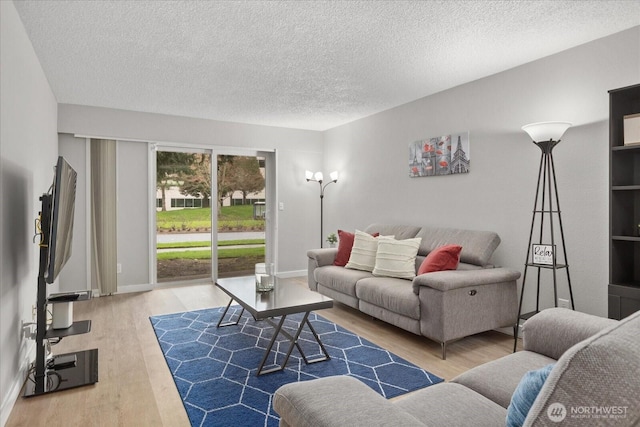 living area featuring a textured ceiling, wood finished floors, and baseboards