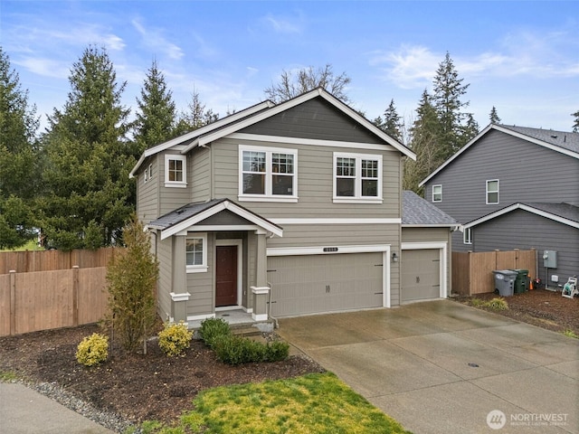 traditional-style home featuring a garage, concrete driveway, and fence