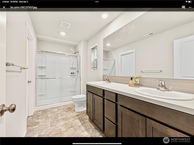 5609 151st Street Ct E, Puyallup, WA 98375 - bathroom with a shower stall, toilet, double vanity, backsplash, and recessed lighting
