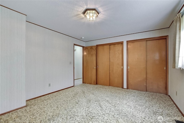 unfurnished bedroom featuring a textured ceiling, two closets, and carpet floors