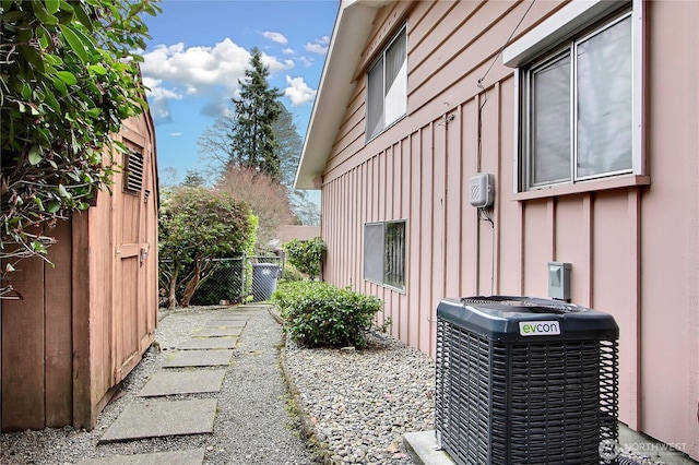 view of property exterior with a gate, board and batten siding, central AC, and fence