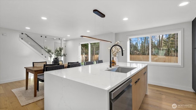 kitchen with recessed lighting, a kitchen island with sink, a sink, dishwasher, and light wood-type flooring