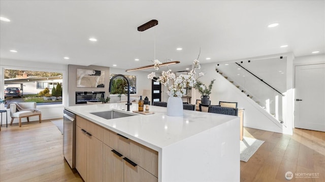 kitchen with light wood finished floors, light brown cabinets, open floor plan, modern cabinets, and a sink