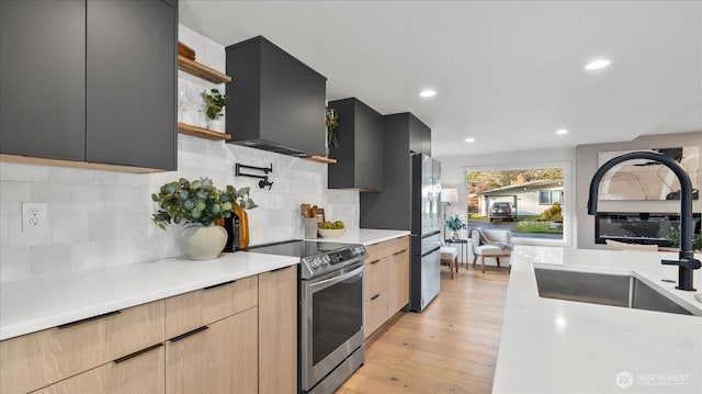 kitchen featuring light wood-type flooring, modern cabinets, a sink, ventilation hood, and stainless steel appliances