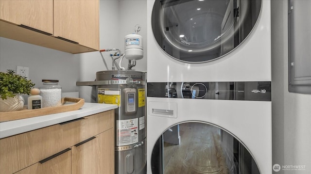 washroom featuring strapped water heater, cabinet space, and stacked washing maching and dryer