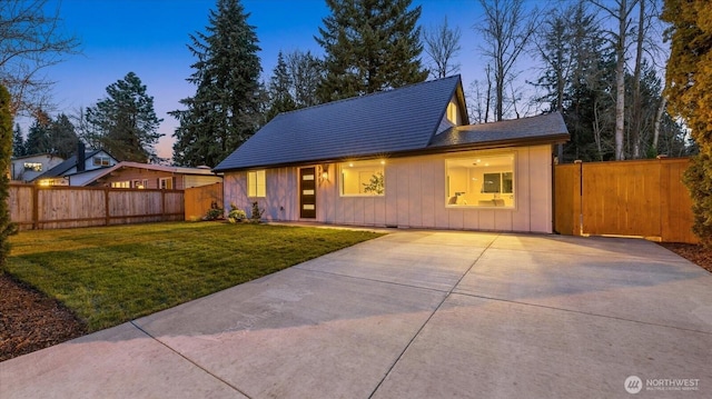 view of front of property with a yard, board and batten siding, driveway, and fence