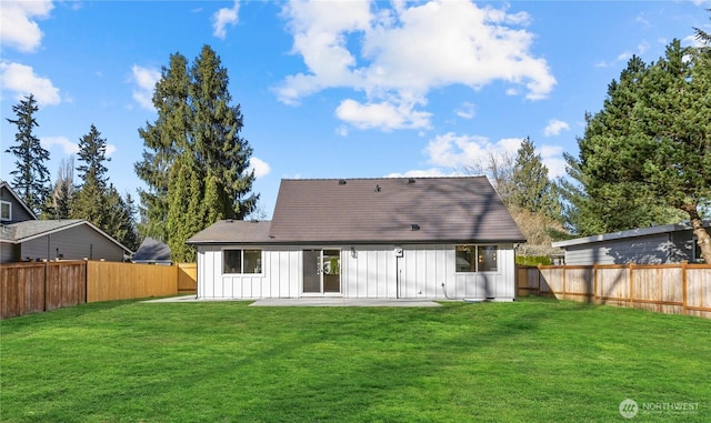 back of property featuring a fenced backyard, a patio area, board and batten siding, and a yard