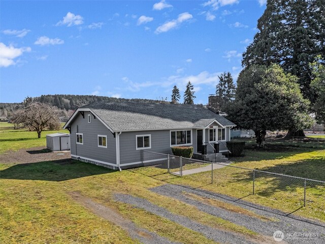 view of front facade with a front yard, a fenced front yard, and a shingled roof