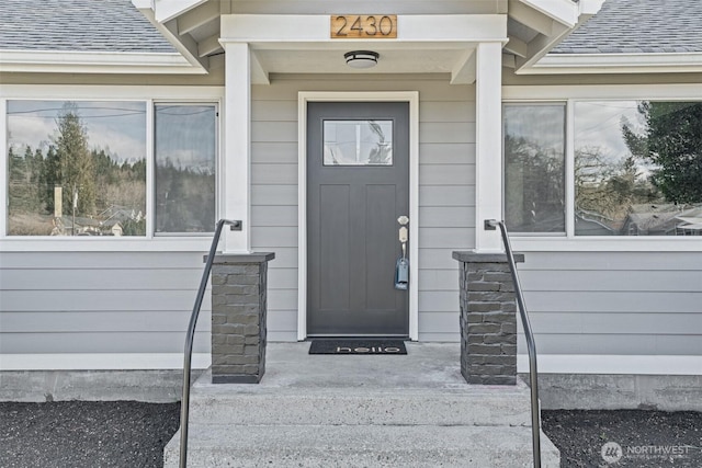 doorway to property with roof with shingles