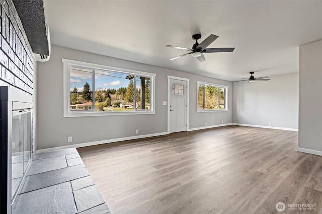 unfurnished living room featuring baseboards, wood finished floors, and a ceiling fan