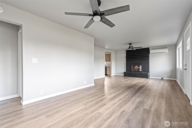 unfurnished living room with light wood-type flooring, baseboards, an AC wall unit, and a fireplace