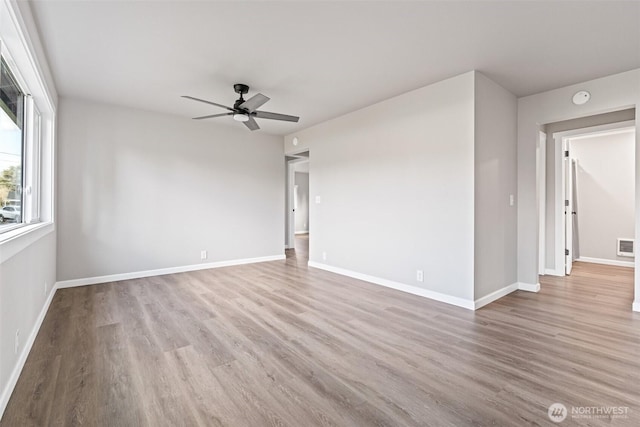 empty room with ceiling fan, baseboards, and wood finished floors